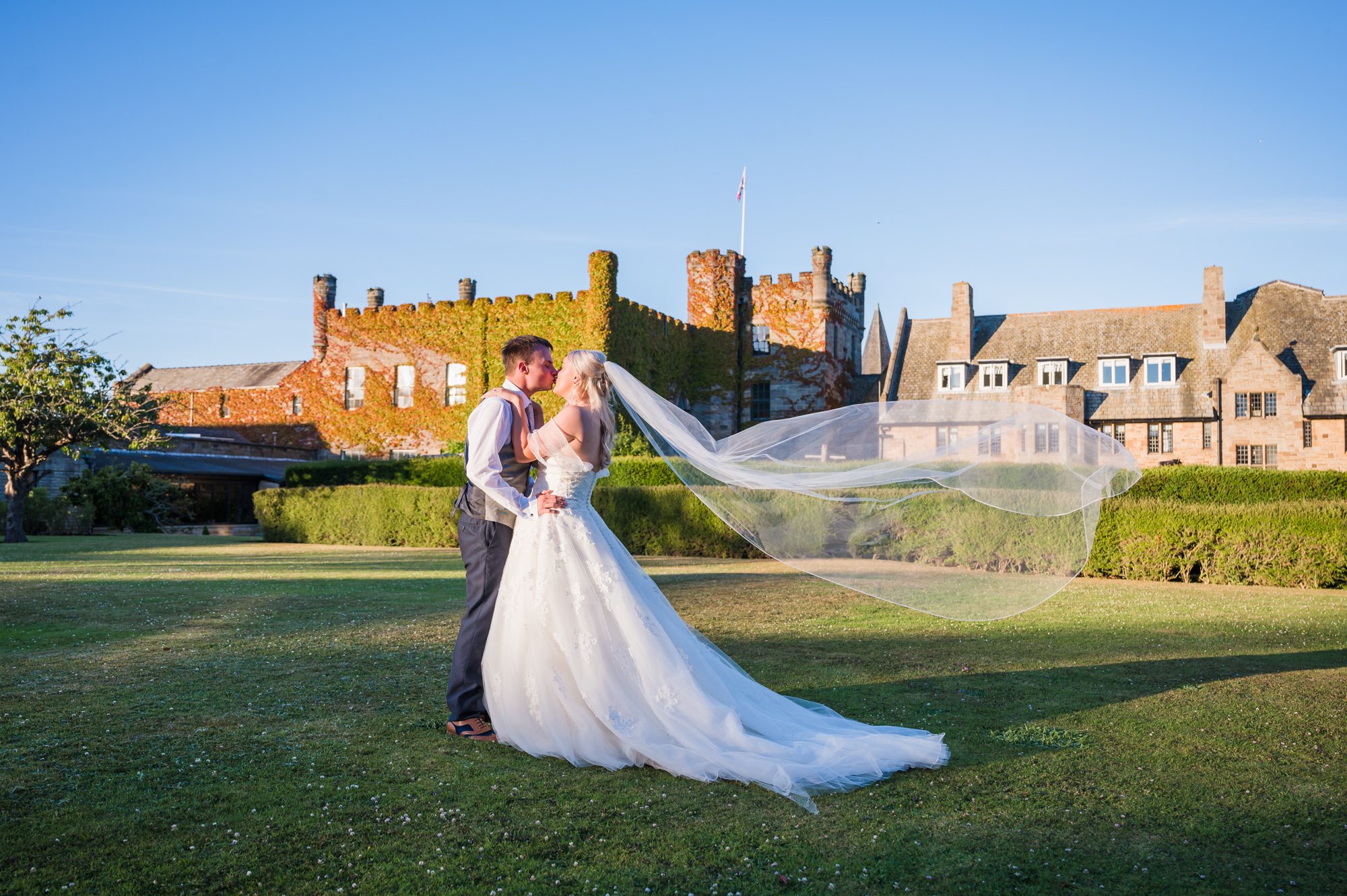 hero shot of bride and groom posing in front of the castle