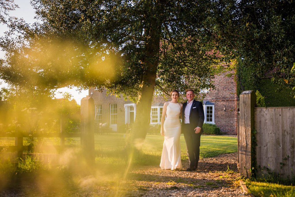 Golden hour portrait of the bride and groom walking through the gates at Hornington Manor, Yorkshire wedding photography.