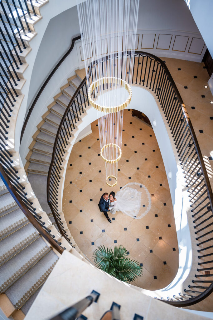 Dramatic overhead view of the bride and groom on the gray grand staircase at Grantley Hall, North Yorkshire.