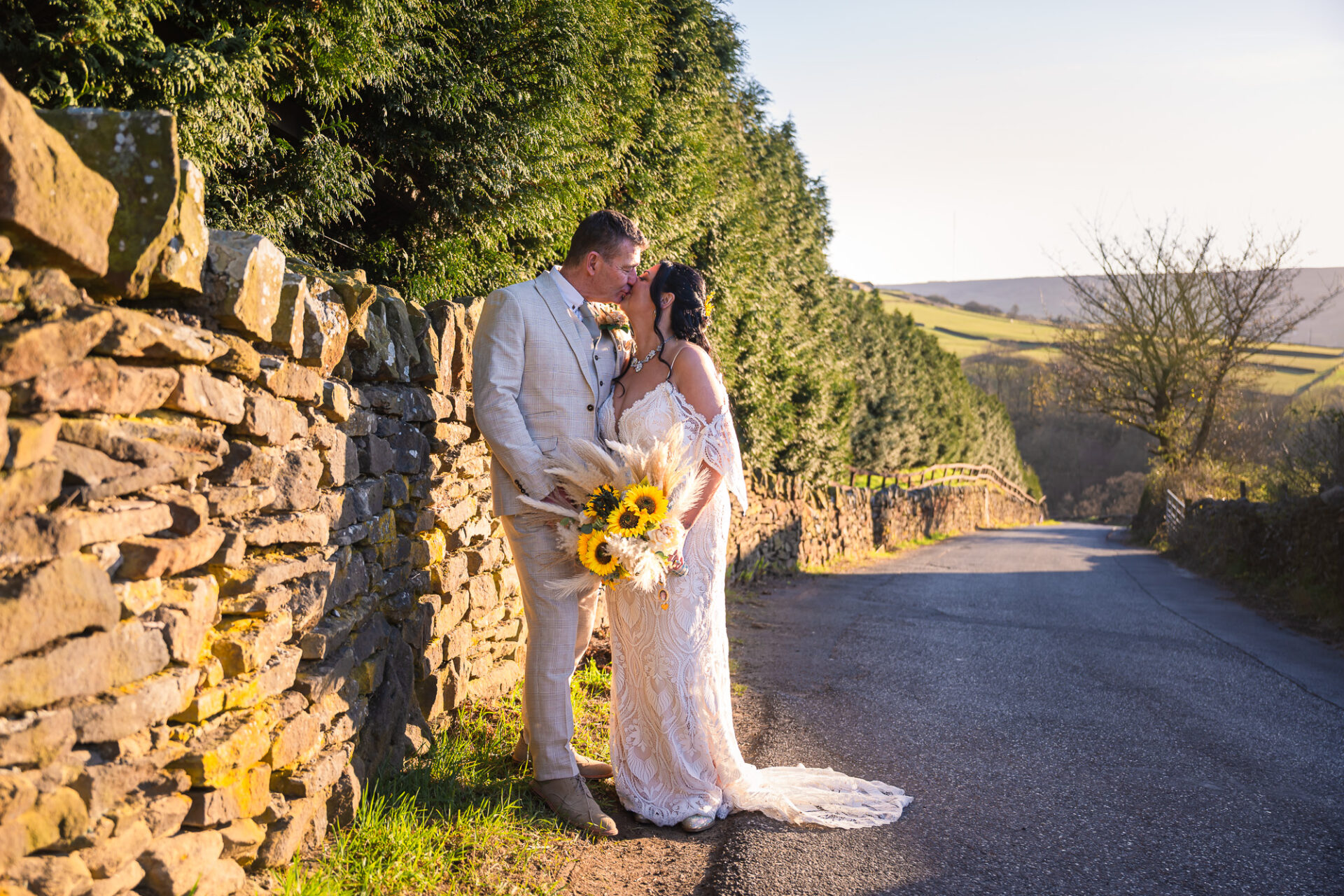 Bride and groom kissing by a rustic stone wall at a Holmfirth vineyard, West Yorkshire wedding photographer.