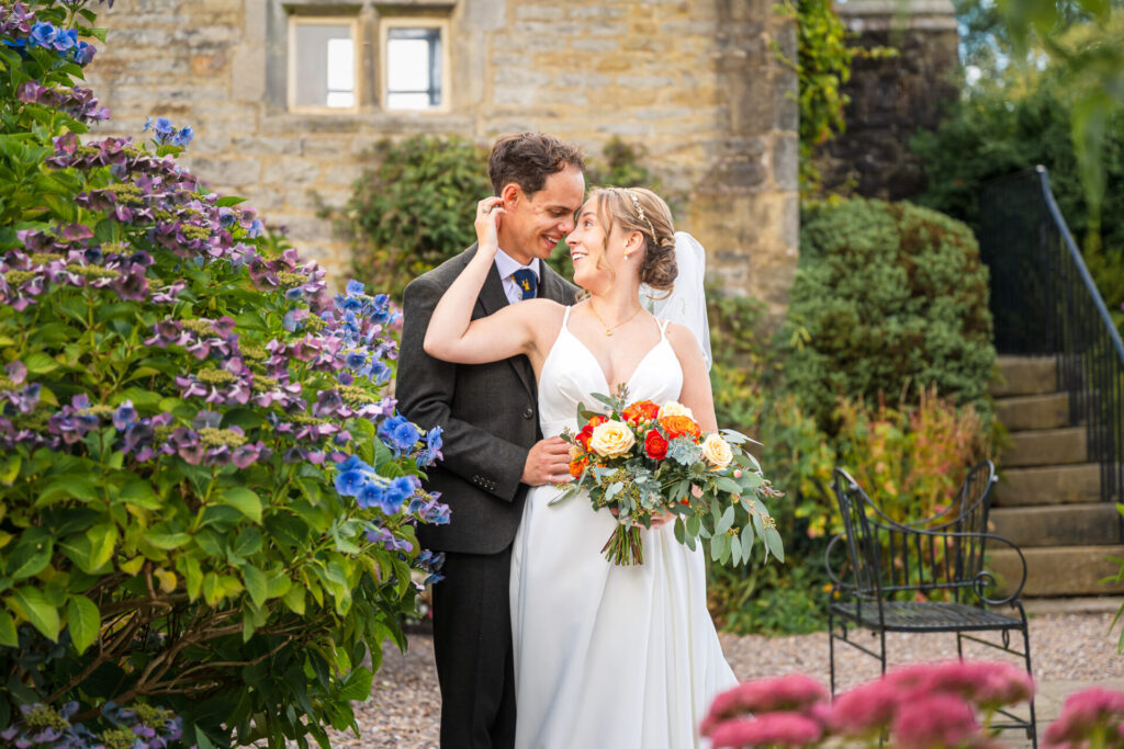 Bride and groom embracing in the stunning gardens at Holdsworth House